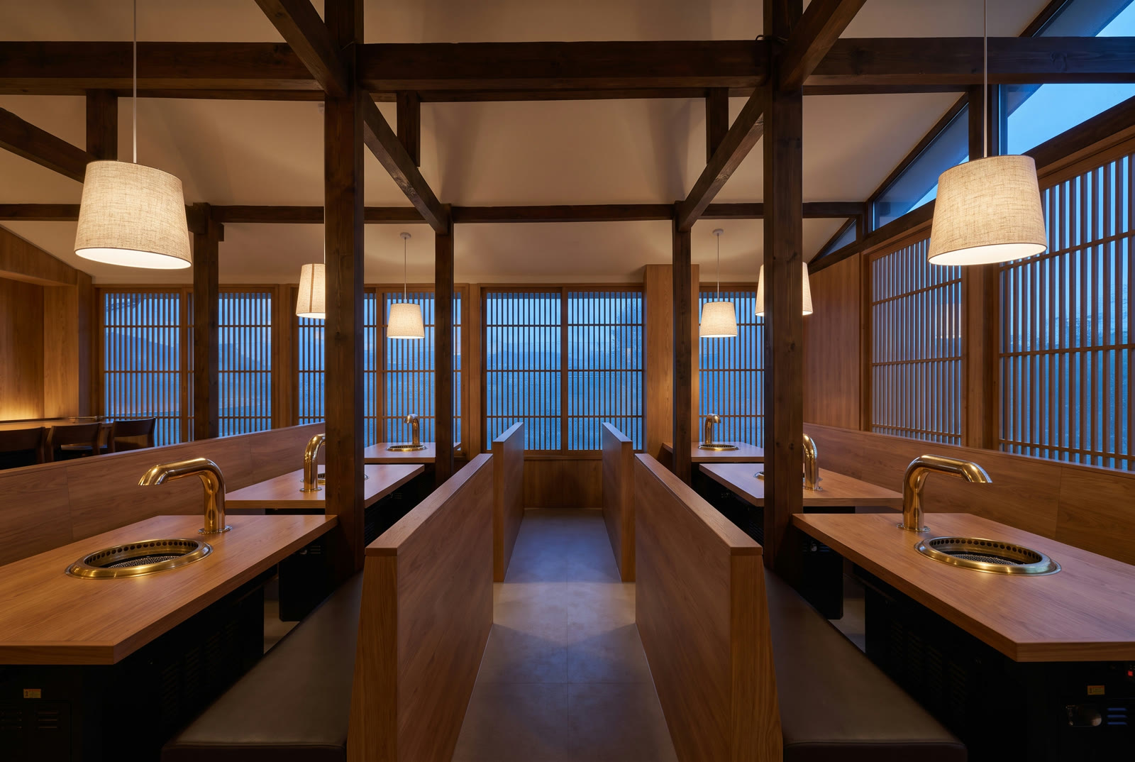 Modern hanok dining room with wood beams and booth seating in evening light
